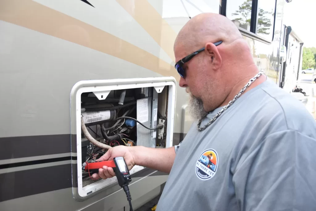 person using a diagnostic tool to troubleshoot an RV refrigerator