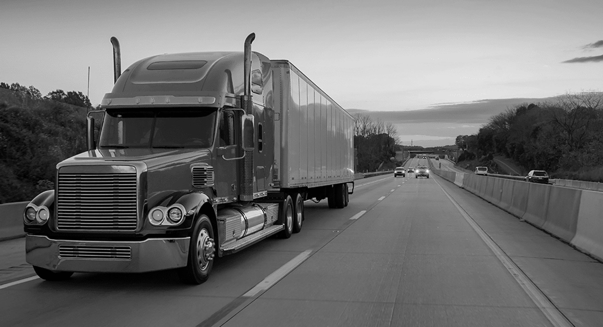 Semi truck driving on a highway at dusk
