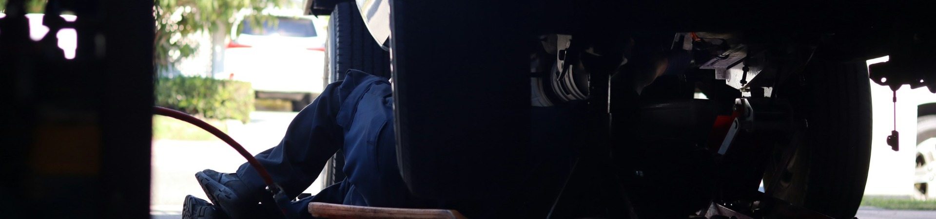 Technician working underneath a truck in a service bay