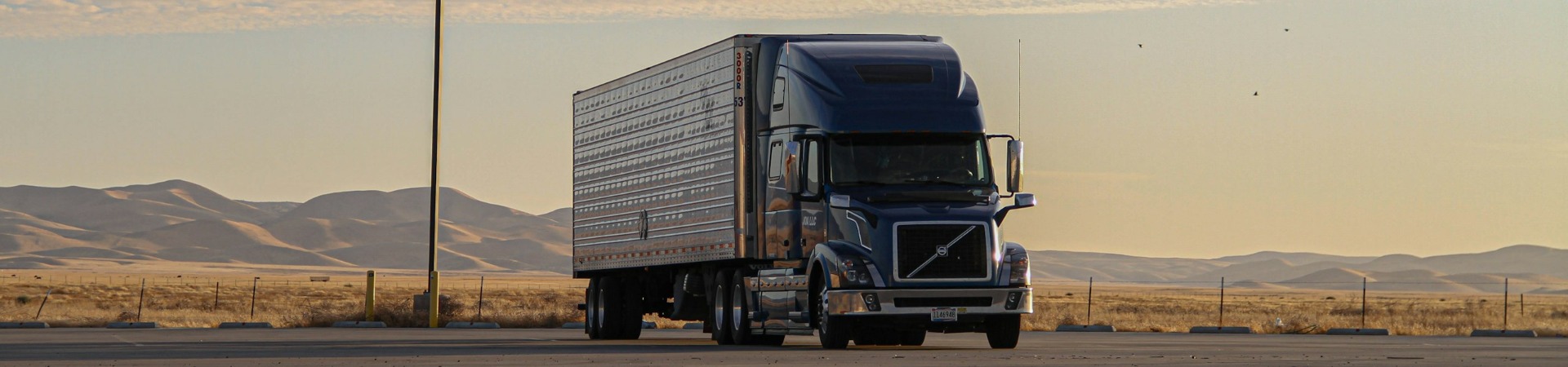 Semi truck and trailer parked on an open highway at sunset
