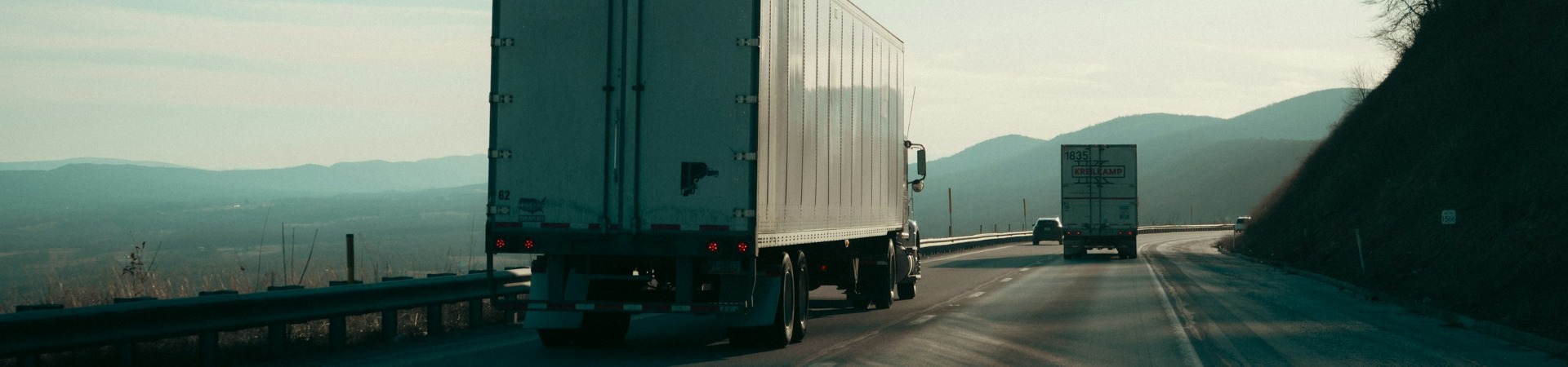 Two semi trucks driving on a mountain highway